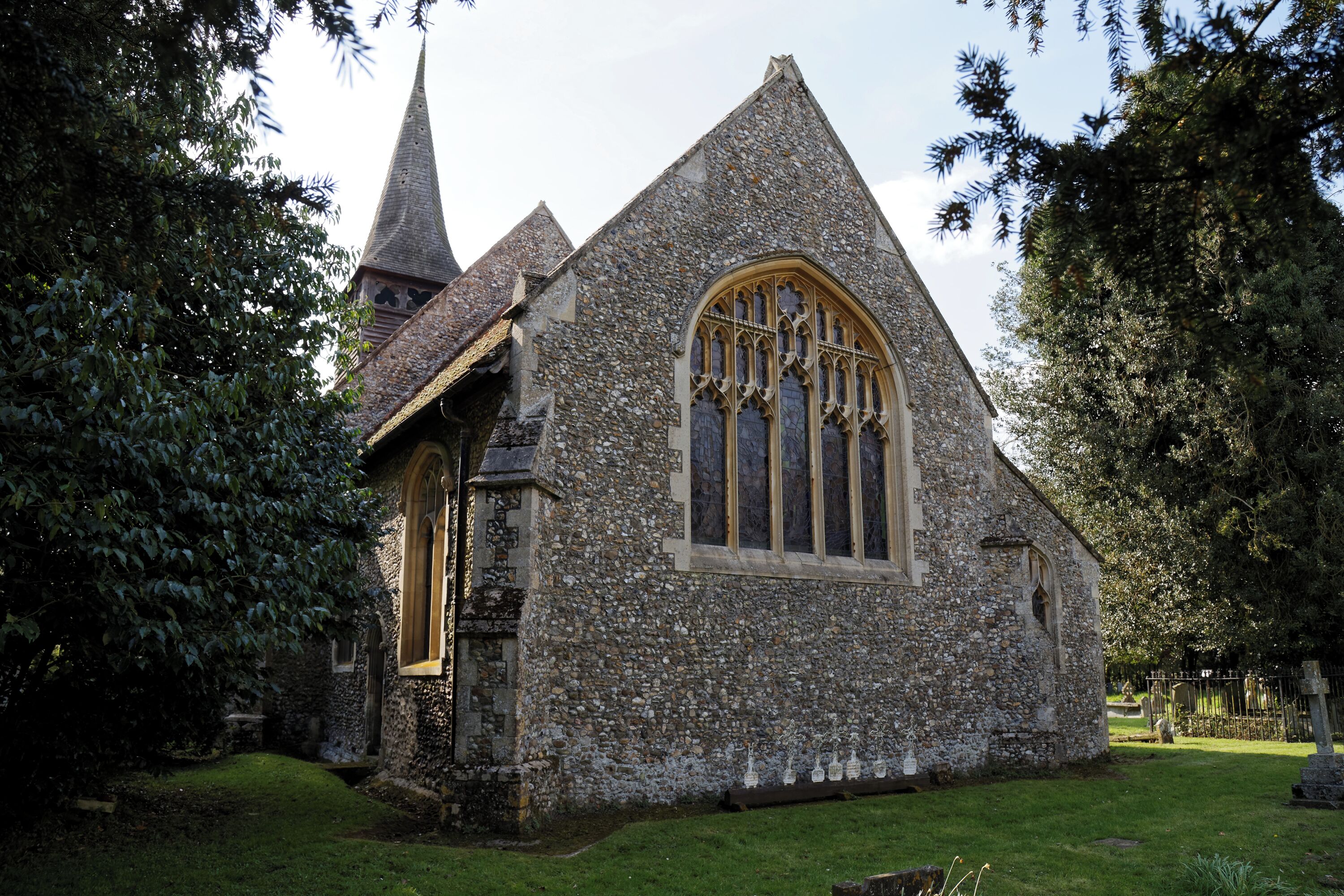 A stone church with a pointed steeple and a large arched window.