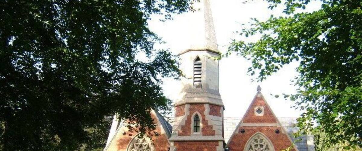 A historic brick church with a tall steeple and pointed arches.