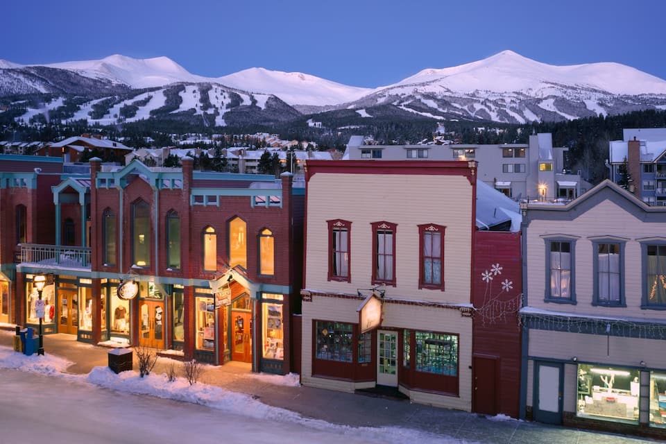 A snow-covered town with historic buildings and a mountain range in the background.