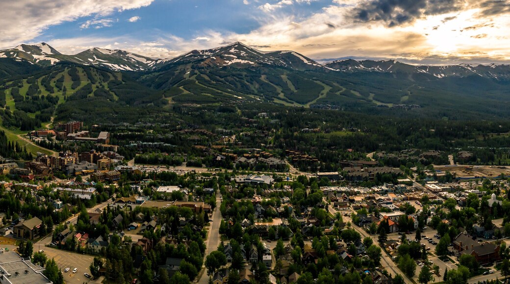 A town nestled between snow-capped mountains, with a mix of residential and commercial buildings, and a prominent ski resort in the background.