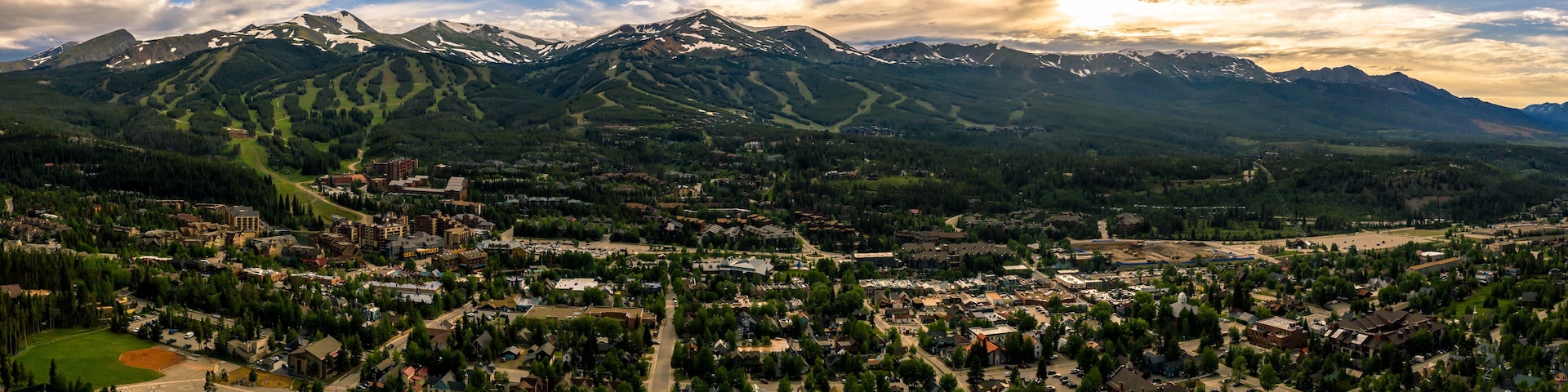 Une ville nichée entre des montagnes enneigées, où se côtoient des bâtiments résidentiels et commerciaux, et où l’on aperçoit, au loin, une station de ski réputée.