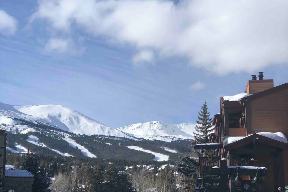 A snowy mountain town with a road leading to a ski rental sign.