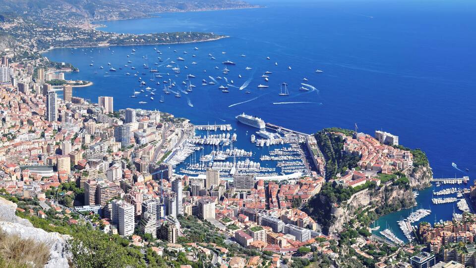 A coastal city with a marina filled with boats, surrounded by buildings and hills.