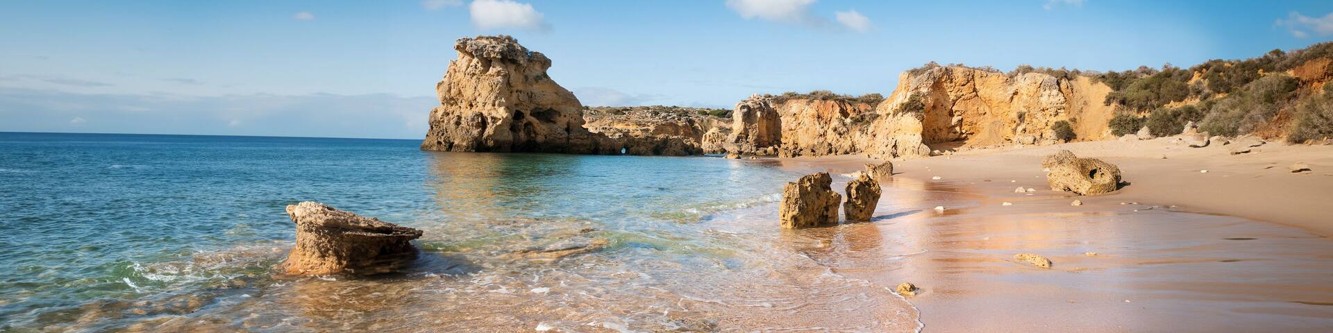 Golden beaches and sandstone cliffs near Albufeira, Portugal Panoramic banner image.