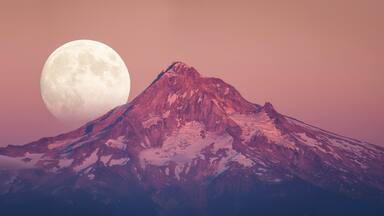 Scenic view of full moon rising behind Mount Hood at dusk