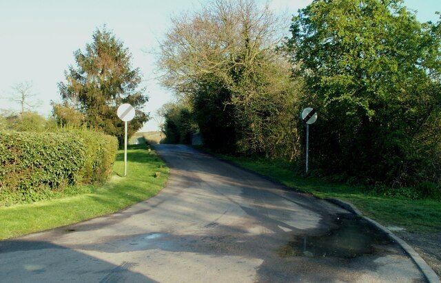 A rural road with a bend, surrounded by greenery and trees.