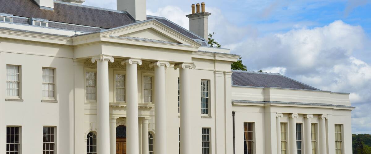 Un grand bâtiment blanc, doté de colonnes, d’un portique et d’une pelouse parfaitement entretenue.