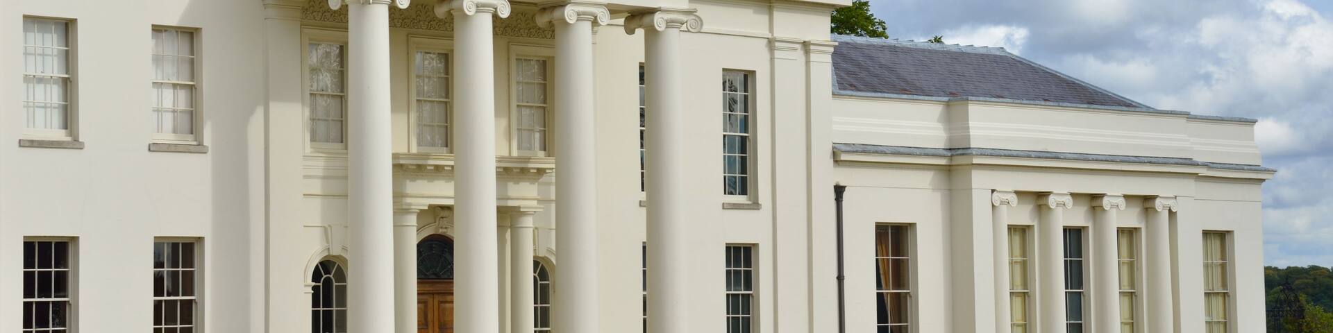 A large white building with columns, a portico, and a well-manicured lawn.