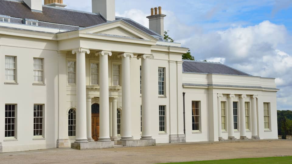 A large white building with columns, a portico, and a well-manicured lawn.