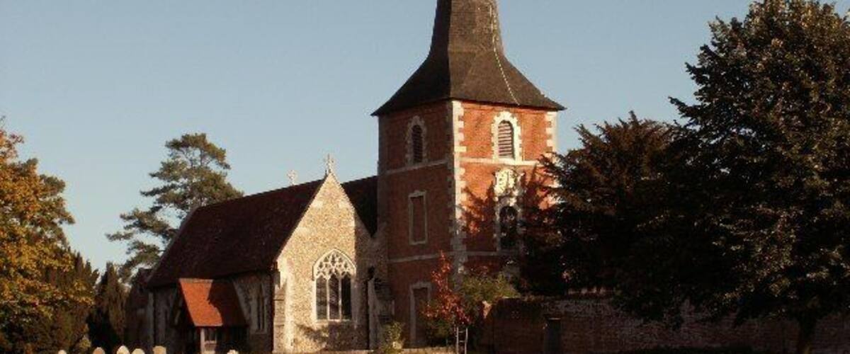 A church with a tall spire and a smaller building with a red roof.