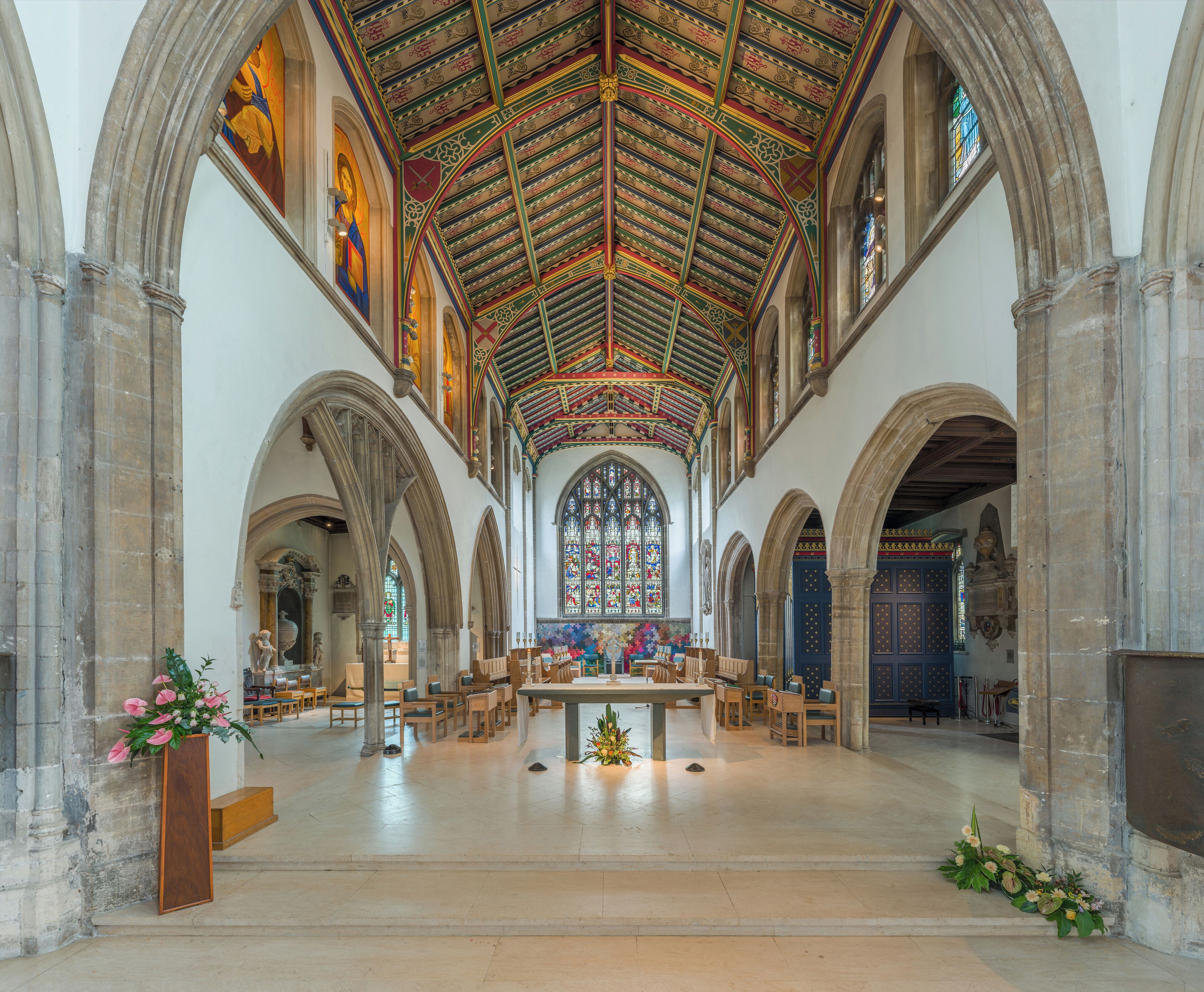 An interior of a cathedral with arched ceilings, stained glass windows, and a central altar.