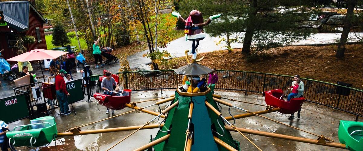 A water ride with green and red boats, a central rotating structure, and a wet ground.