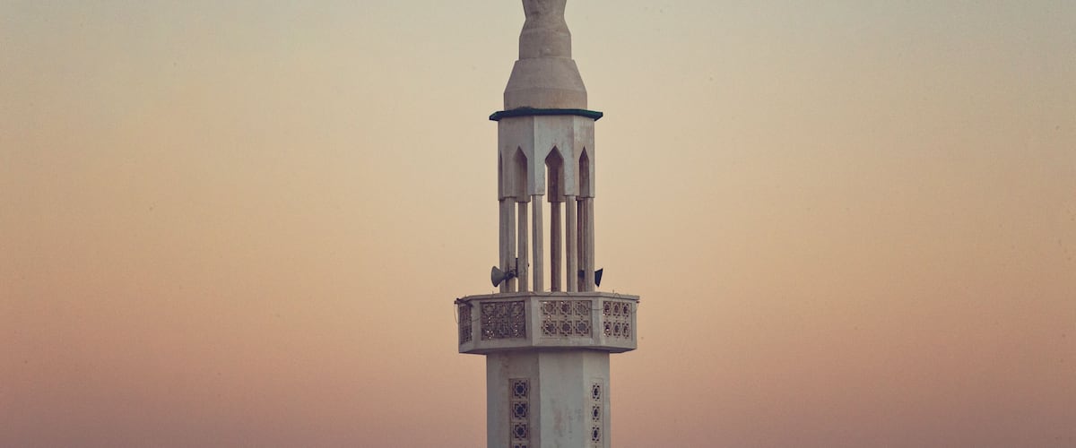 A mosque minaret with a decorative top and a patterned base.