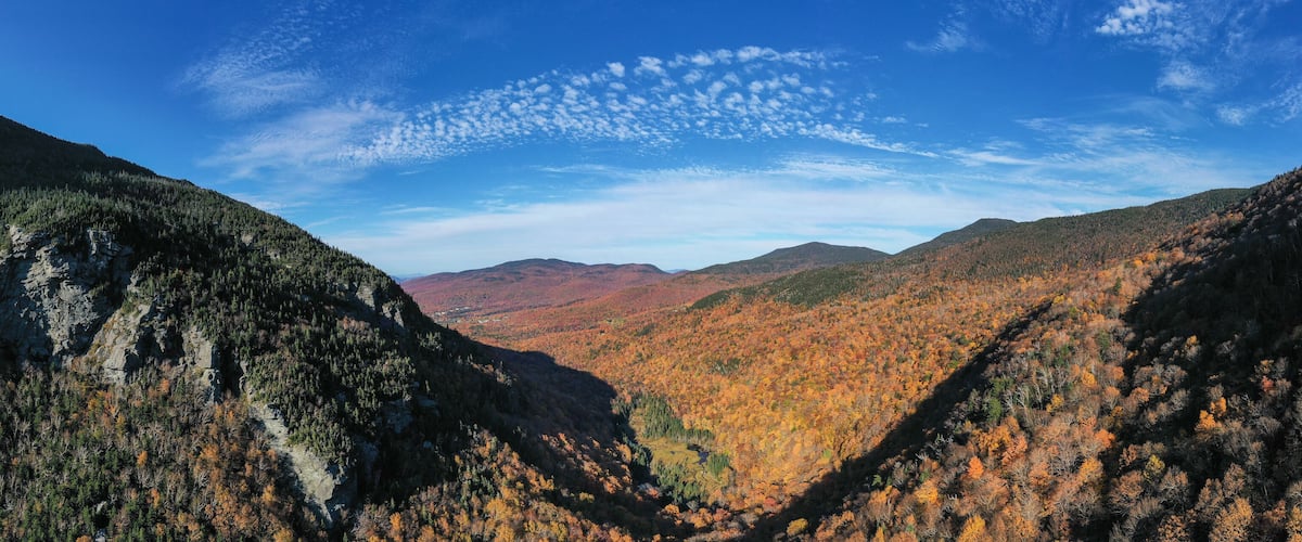 A canyon with autumn foliage and a clear blue sky.