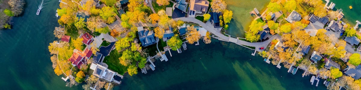 An aerial view of a residential area with houses, a dock, and a body of water.