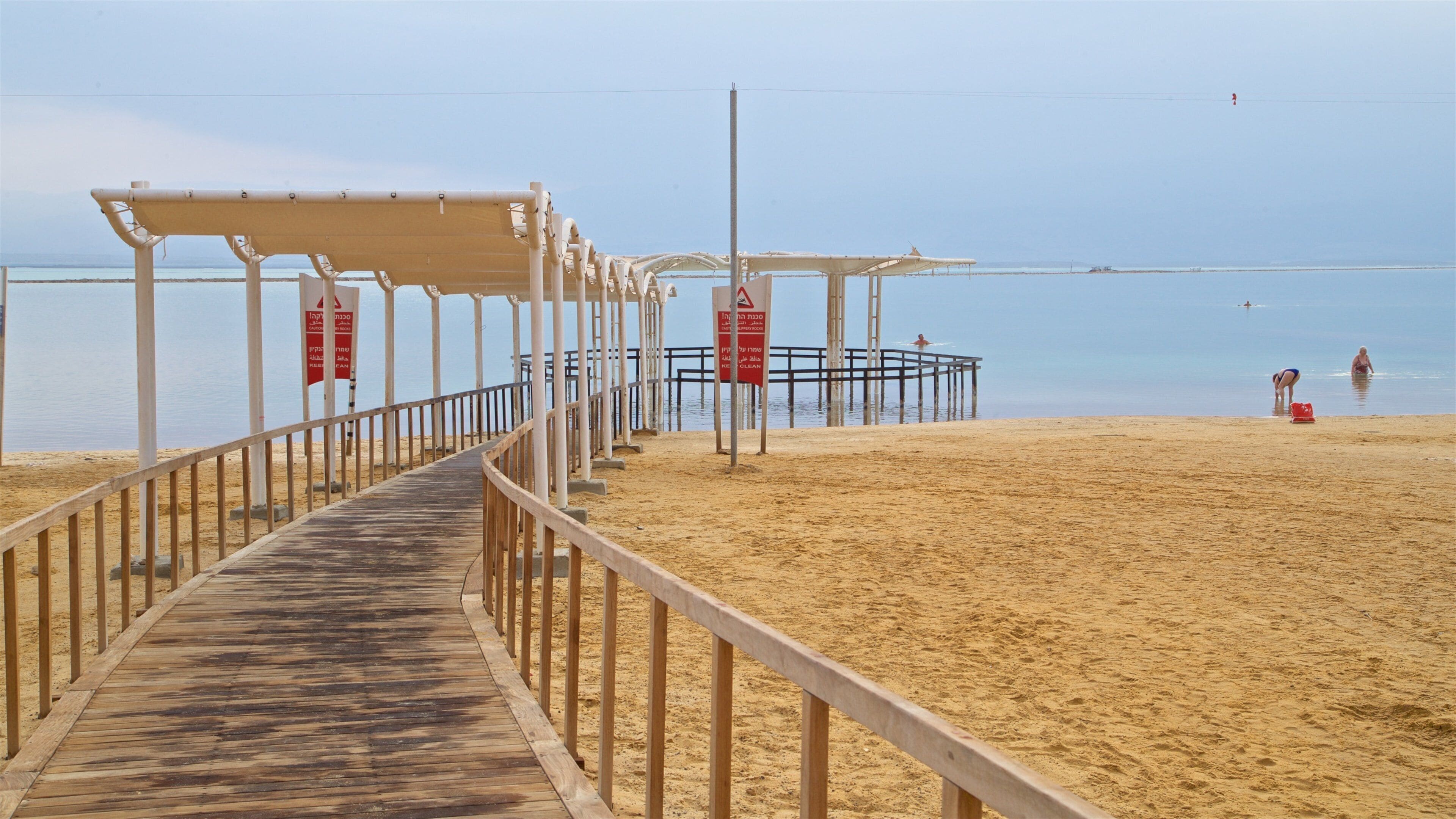 Um calçadão de madeira que leva a uma praia com um píer e um posto de salva-vidas.
