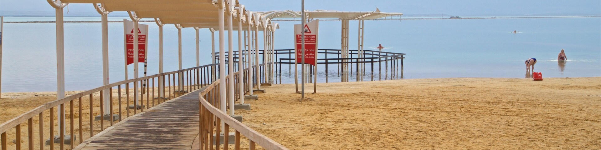 Um calçadão de madeira que leva a uma praia com um píer e um posto de salva-vidas.