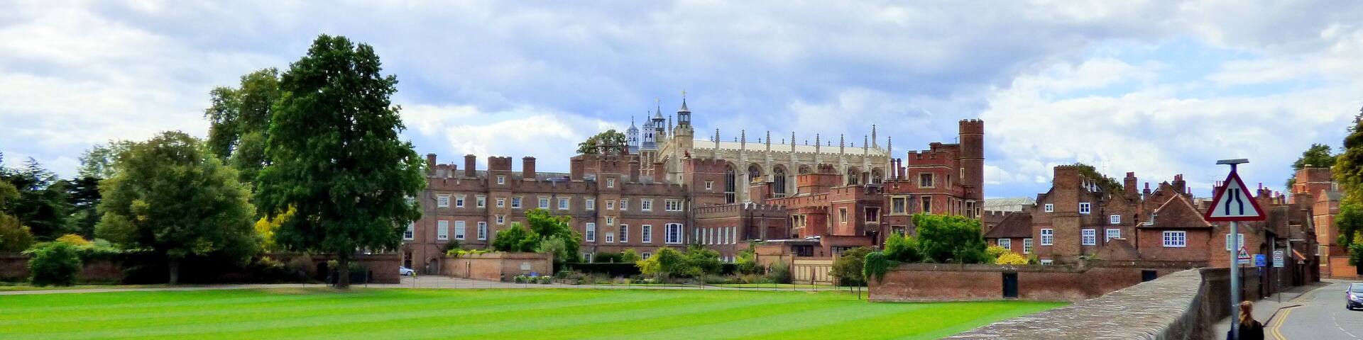 A historic castle with a large lawn in the foreground.
