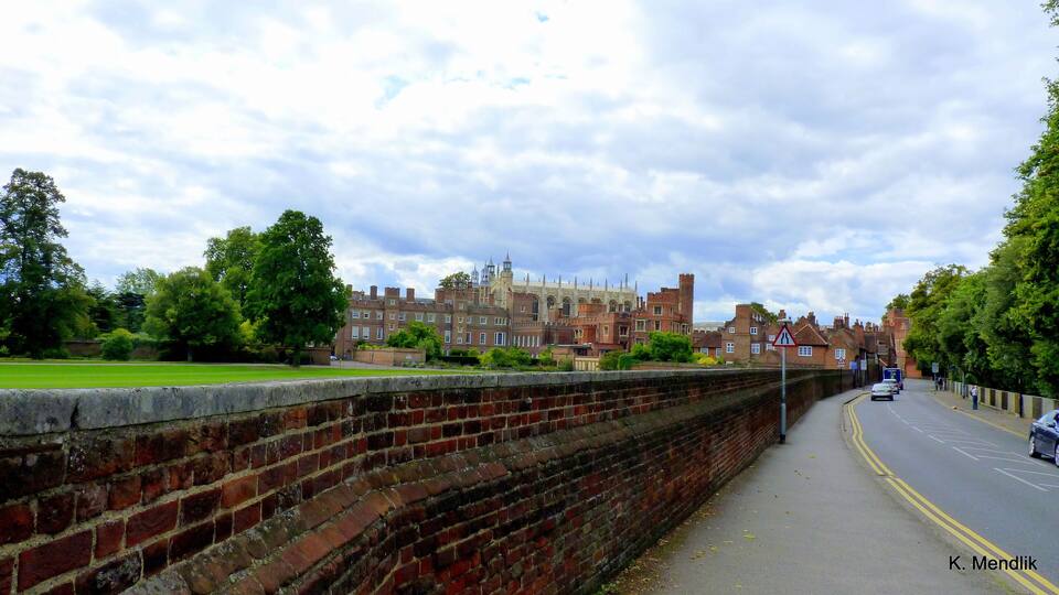 A historic building with red brick walls and a paved road with cars.
