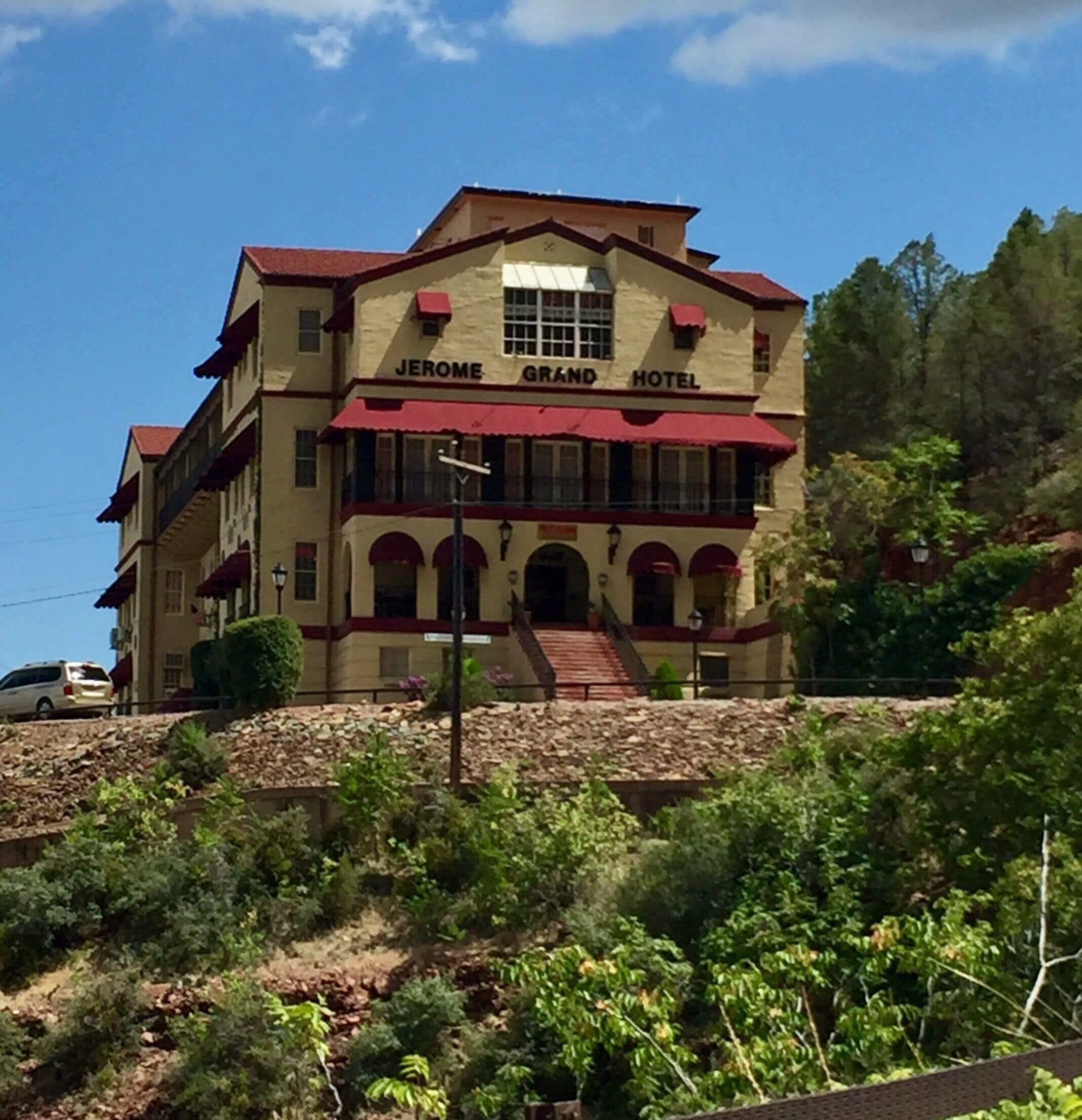 The Jerome Grand Hotel with a red roof and beige walls, surrounded by greenery.