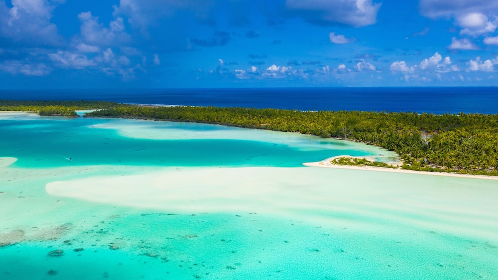 A turquoise lagoon surrounded by lush greenery and a clear blue sky.