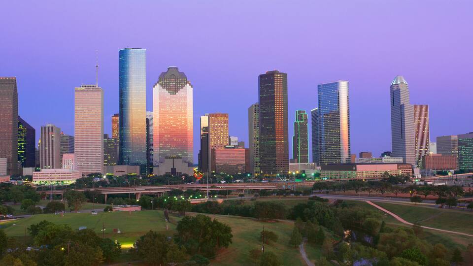 A city skyline with tall buildings and a park in the foreground.