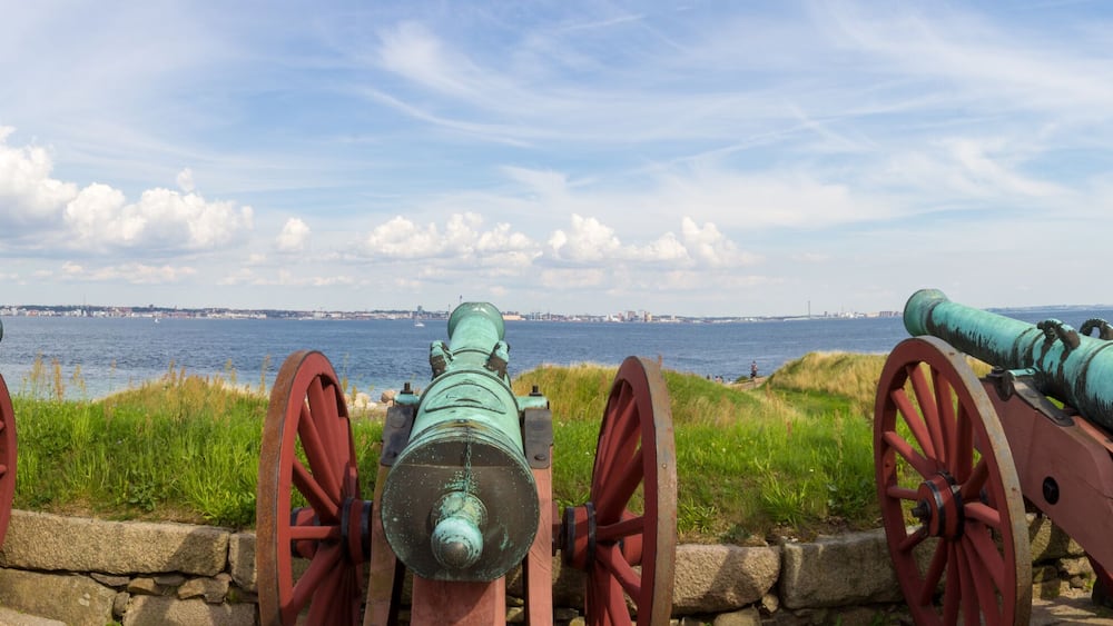 Panoramic view of old historic canons pointed to the ocean and Helsingborg Sweden seen accross the sound
