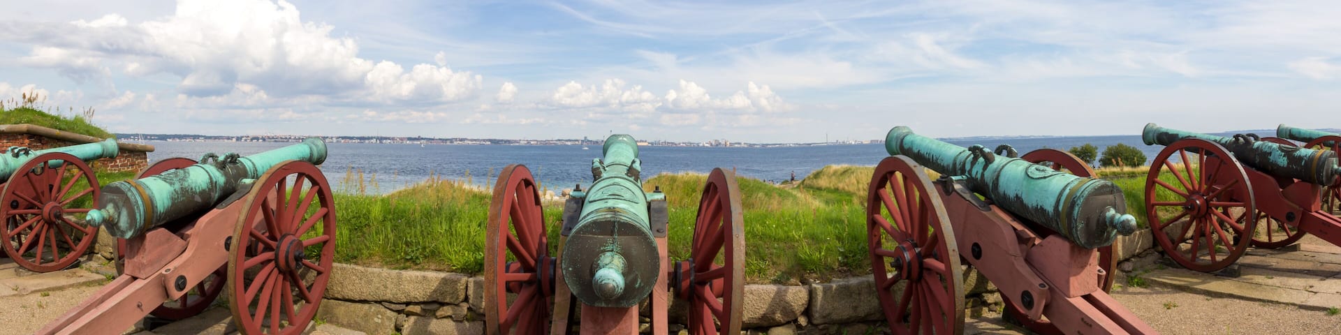 Panoramic view of old historic canons pointed to the ocean and Helsingborg Sweden seen accross the sound