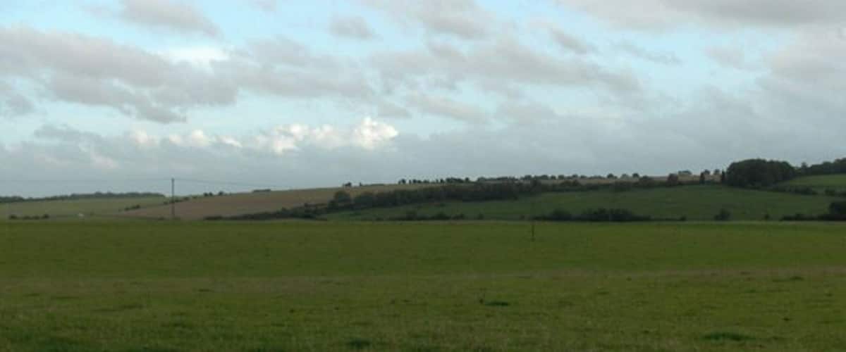 A vast green field with rolling hills in the background.