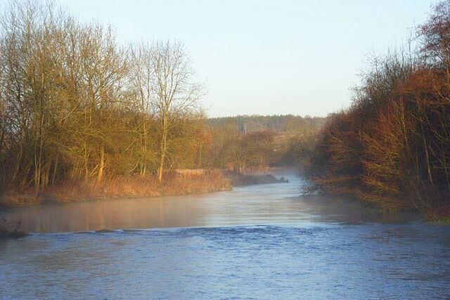 The River Kennet, Chilton Foliat Looking upstream from the footbridge on the footpath to the south of the village. A small weir creates the difference in the appearance of the surface of the water.