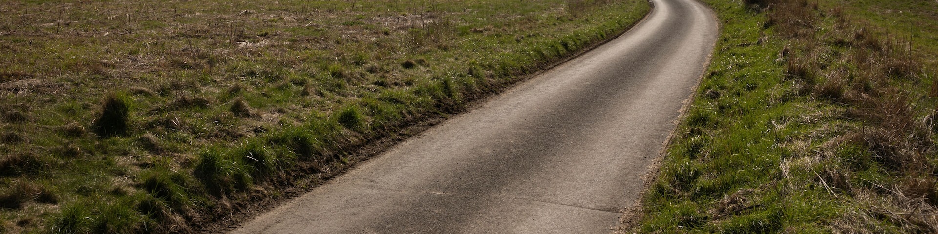Empty single track country lane running down through open farmland with dramatic sky above, School Lane, East Garston, Berkshire, England, United Kingdom, Europe