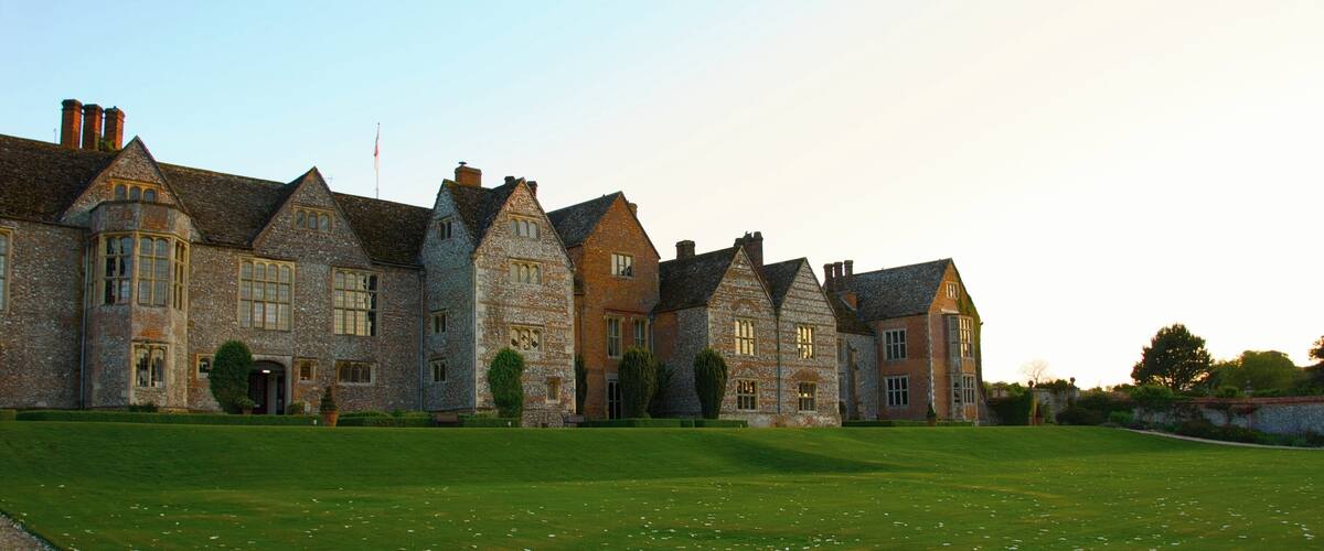 A large stone building with multiple chimneys and a well-maintained lawn.