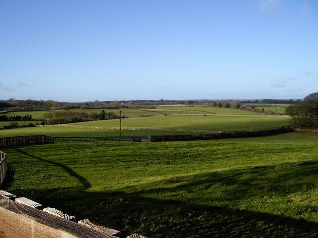 A green field with a stone wall and a fence.