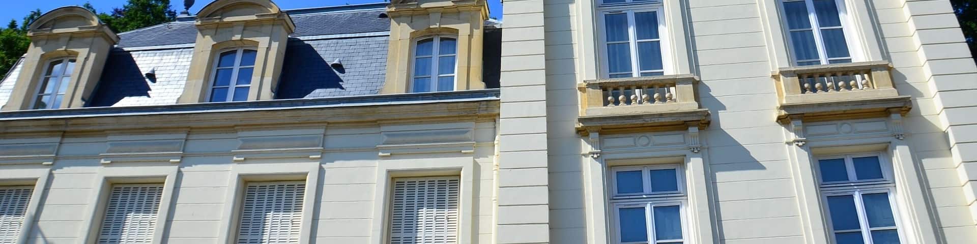 A classical building with a mansard roof and multiple windows.