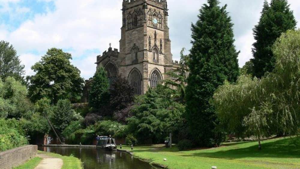 A historic church with a tall tower and a canal in the foreground.