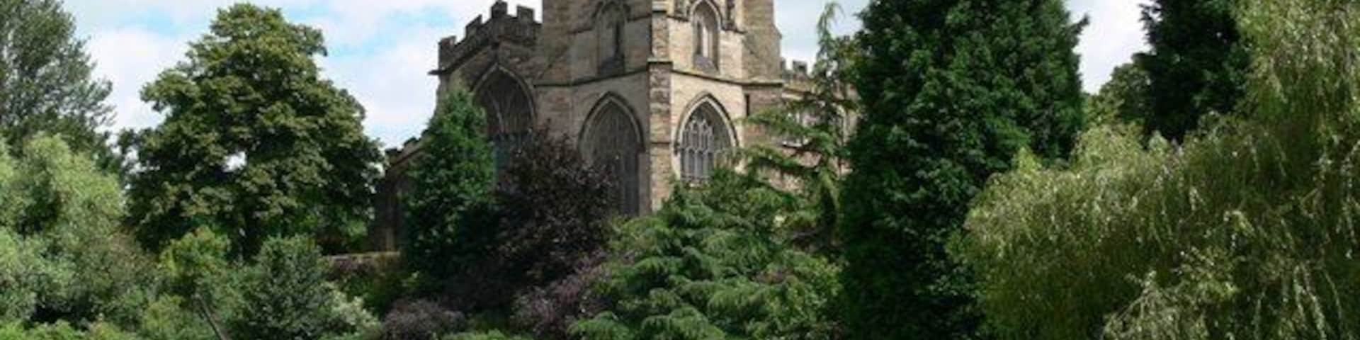 A historic church with a tall tower and a canal in the foreground.