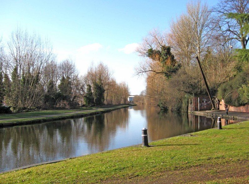 A calm river with grassy banks and leafless trees.