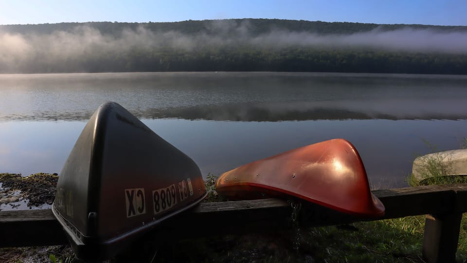 A lake with a wooden dock and a boat.