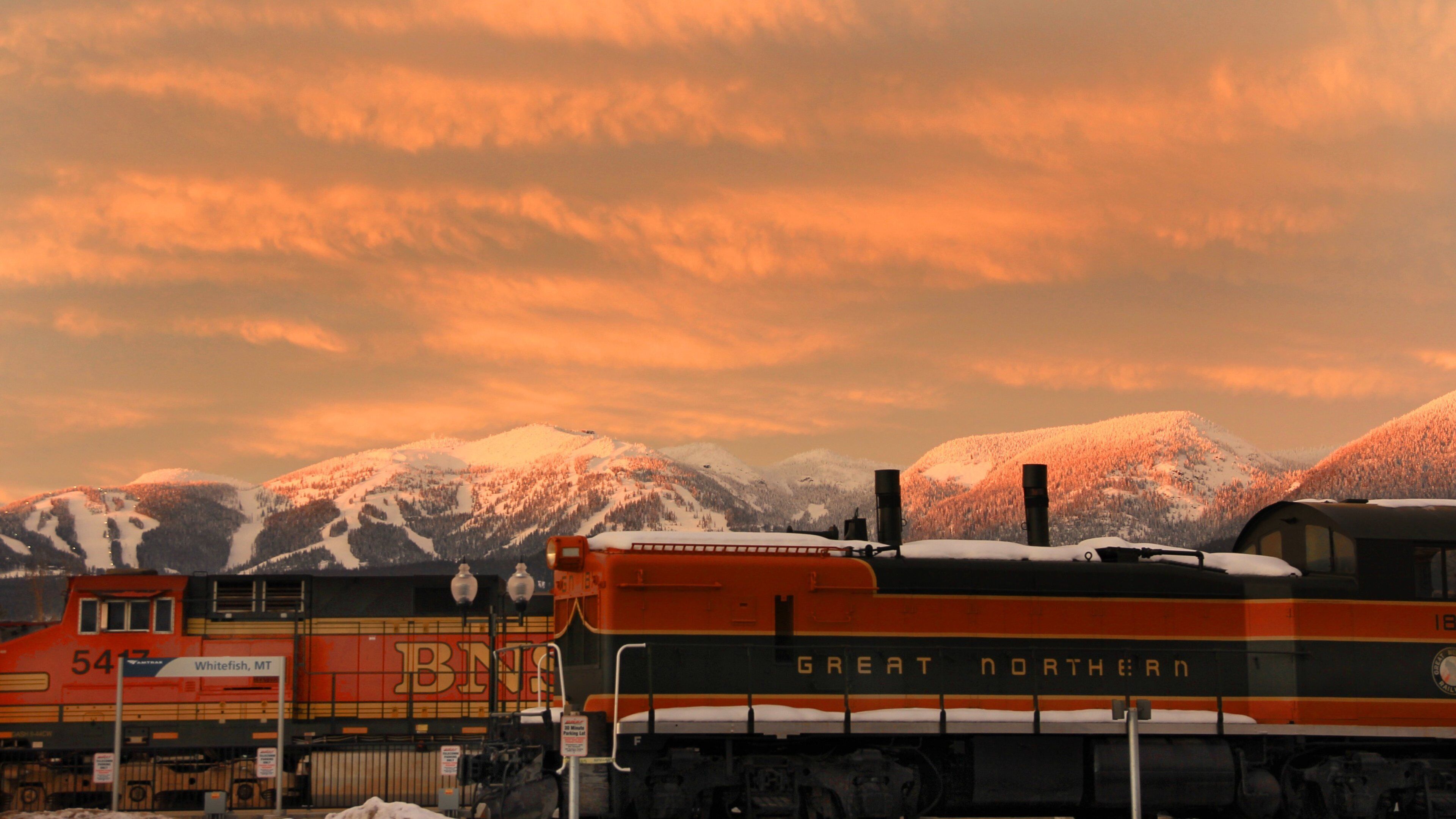 A train with the text "Great Northern" and "Whitefish, MT" in a snowy landscape with mountains in the background.