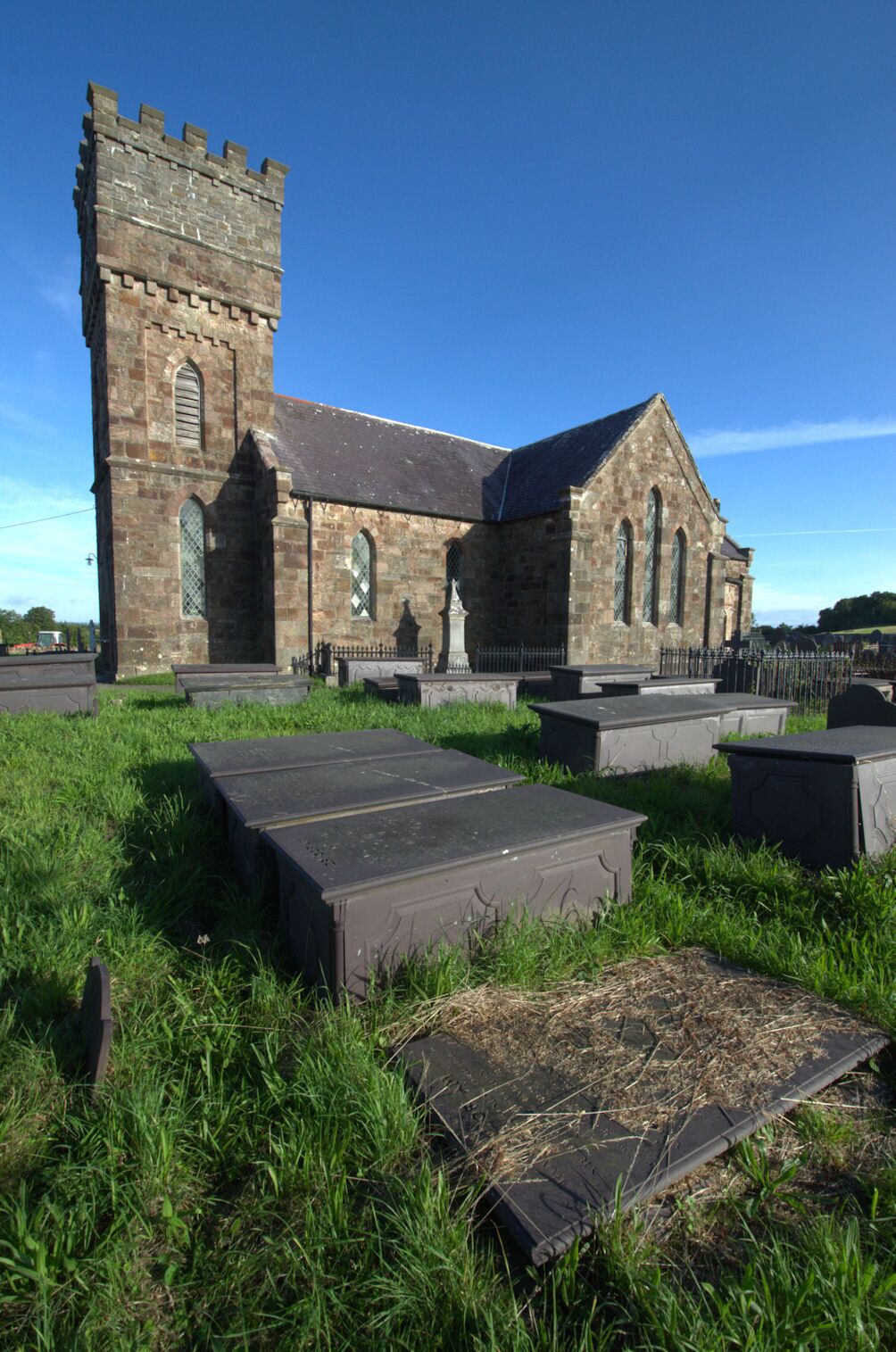 A historic church with a tall tower and a cemetery in front.