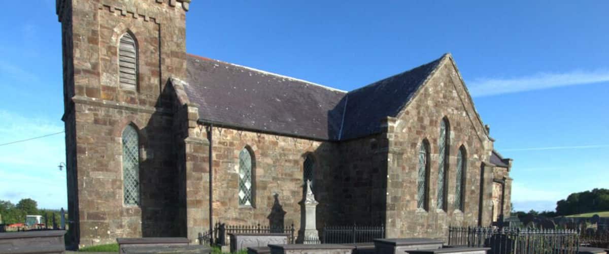 A historic church with a tall tower and a cemetery in front.