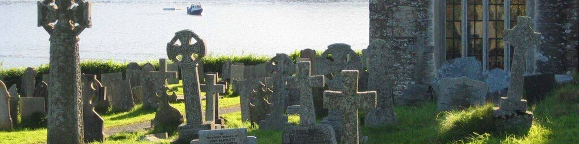 St Winnow parish churchyard, Cornwall, with the east window of the south aisle of the church. Beyond is the Fowey estuary.