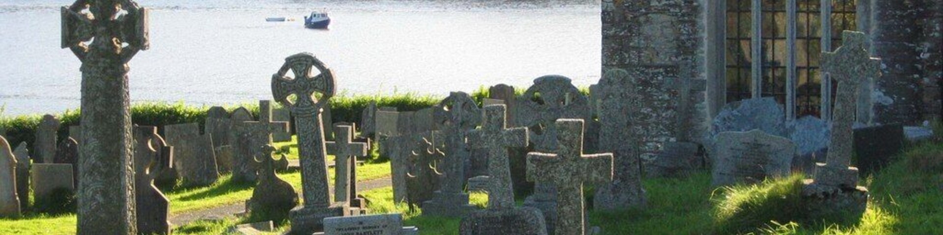 St Winnow parish churchyard, Cornwall, with the east window of the south aisle of the church. Beyond is the Fowey estuary.