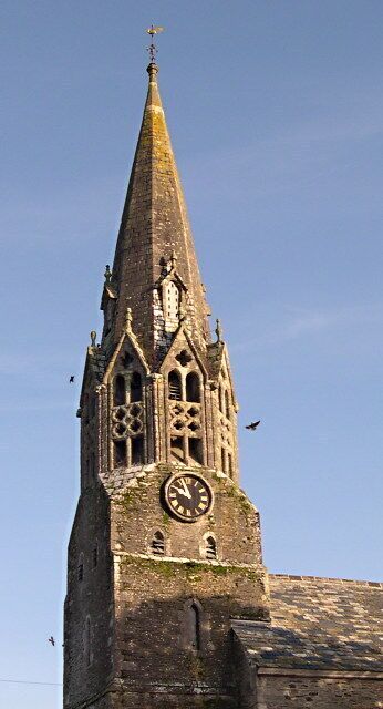 A tall church tower with a clock and a weather vane.