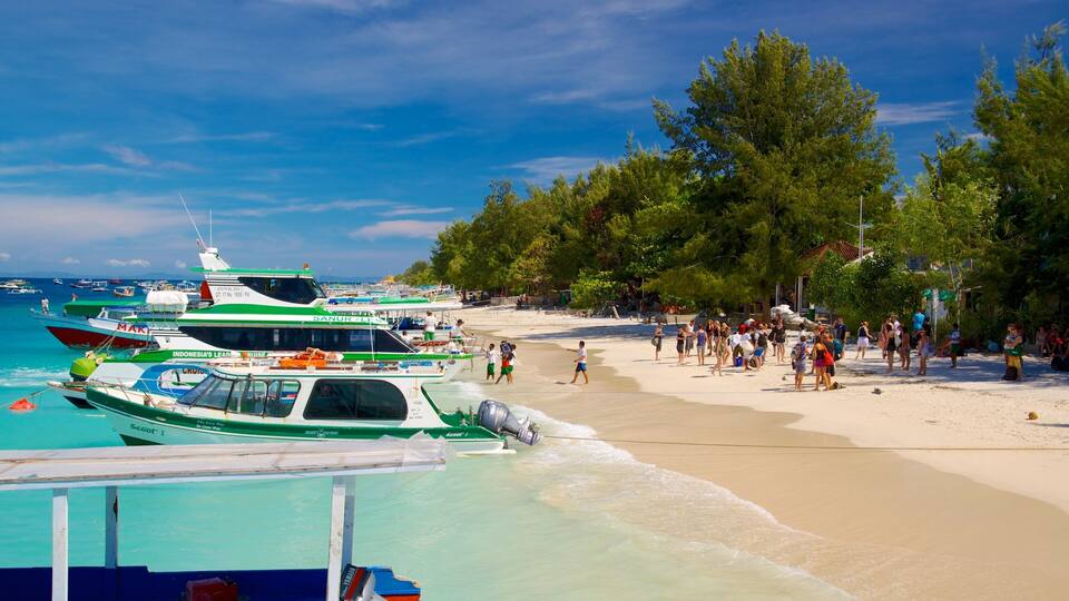 A beach with boats docked and people walking on the sand.