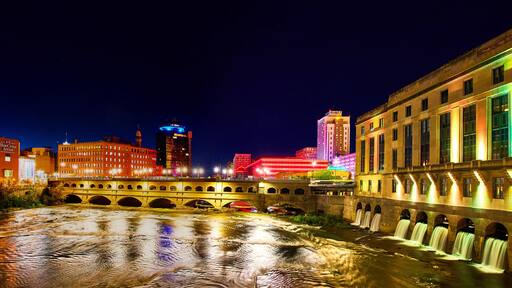 Manmade waterfalls and river in Rochester New York at night with city lights