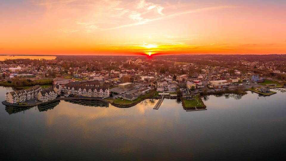 A coastal town at sunset with a bridge over a calm lake.