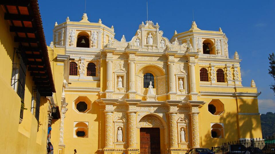 A large, ornate yellow colonial church with multiple statues and arches.