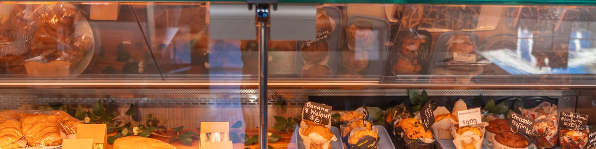 Vitrina de panadería con diversas opciones de productos horneados y sus precios.