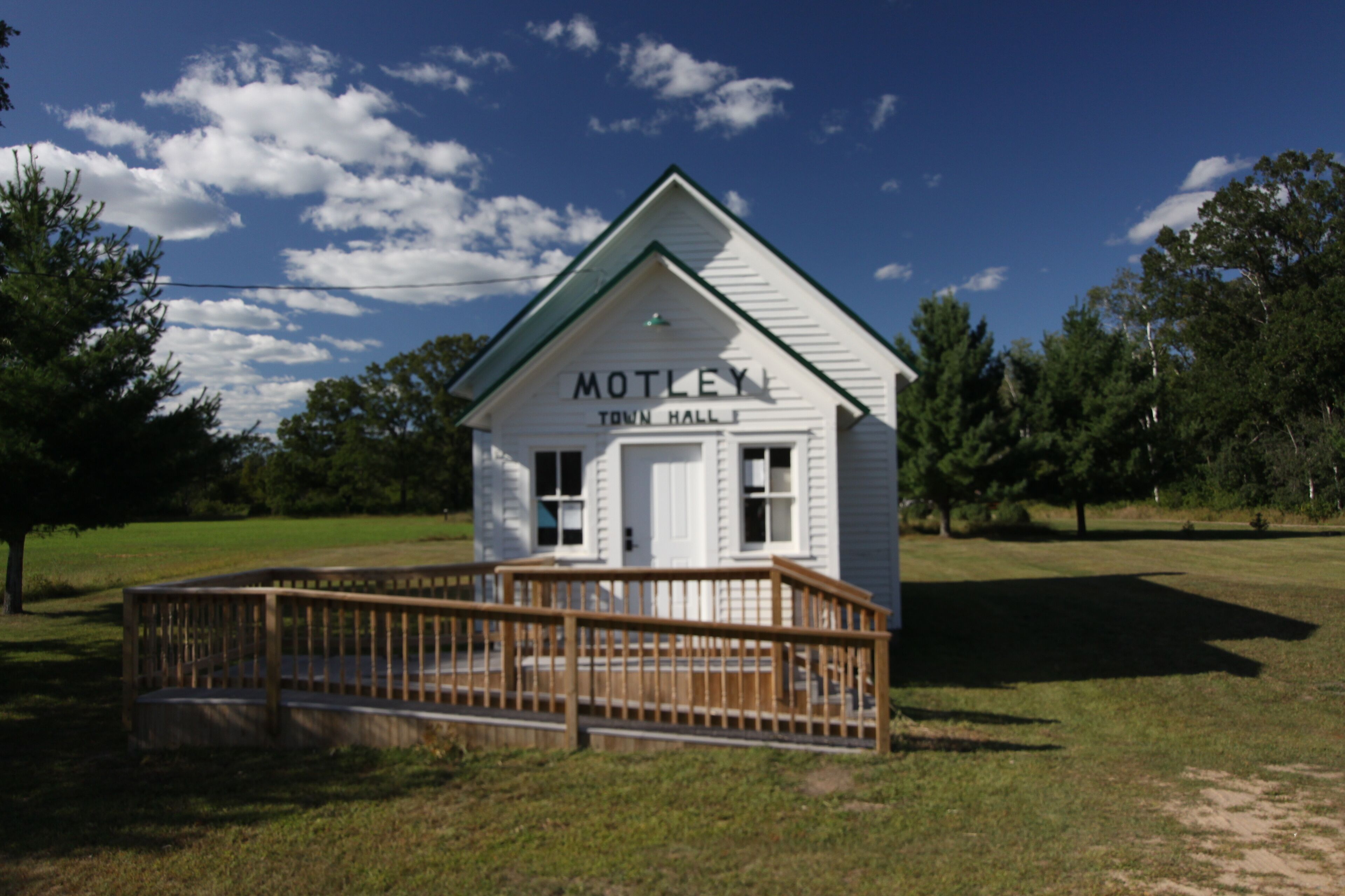 A white building labeled "MOTLEY TOWN HALL" with a wooden deck in front.